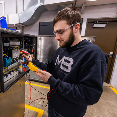 An automated packaging student working with equipment in the lab