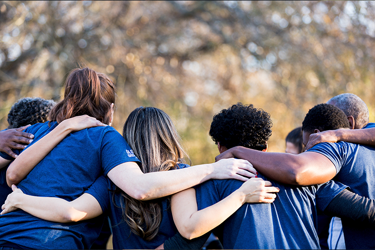 group of people with their arms around each others shoulders, facing away from the camera