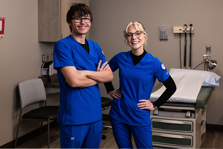 two smiling cma students standing in a classroom