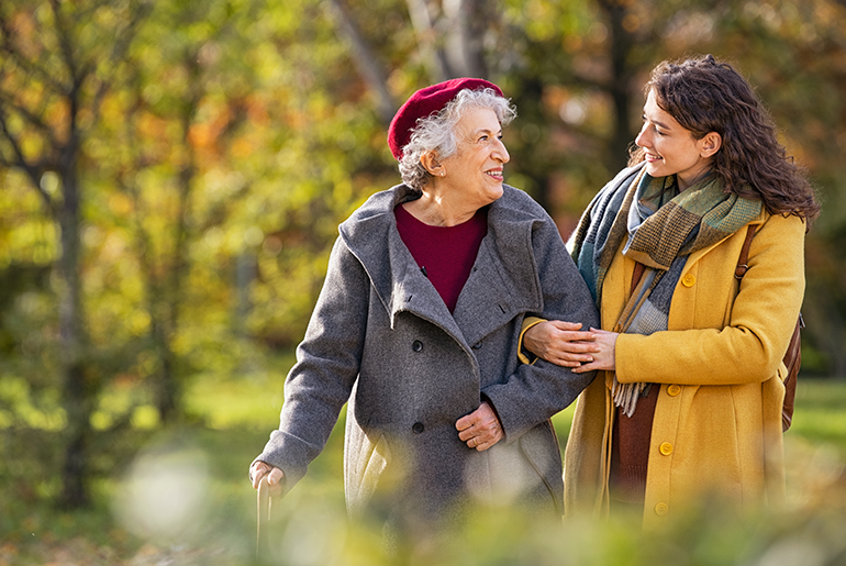 smiling caregiver and patient smiling while taking a walk outside on a fall day