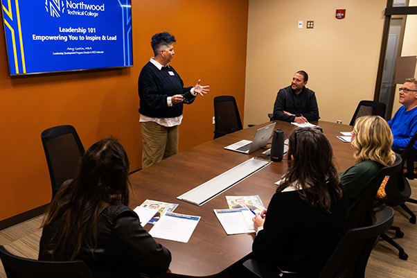 group of five people sitting in a conference room watching a leadership presentation