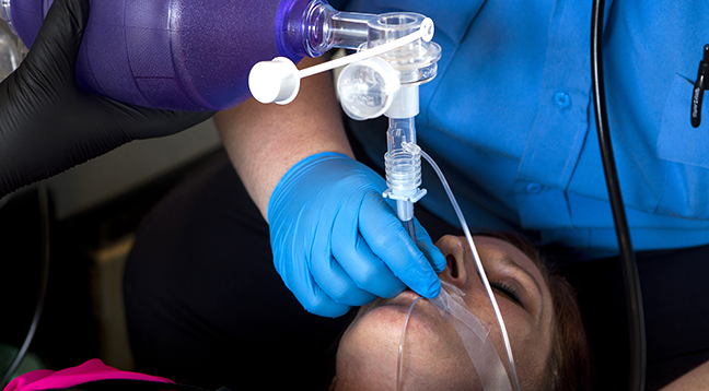 A student practicing EMT techniques on a fellow classmate