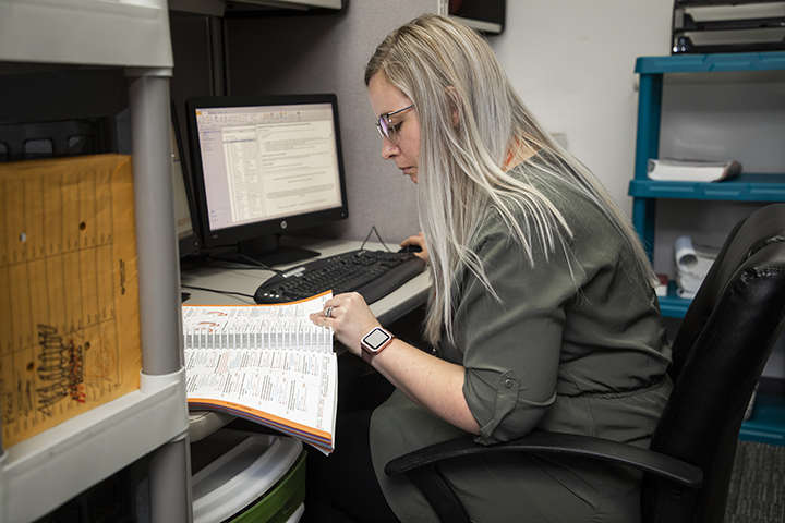 A medical administrative professional referencing a medical textbook