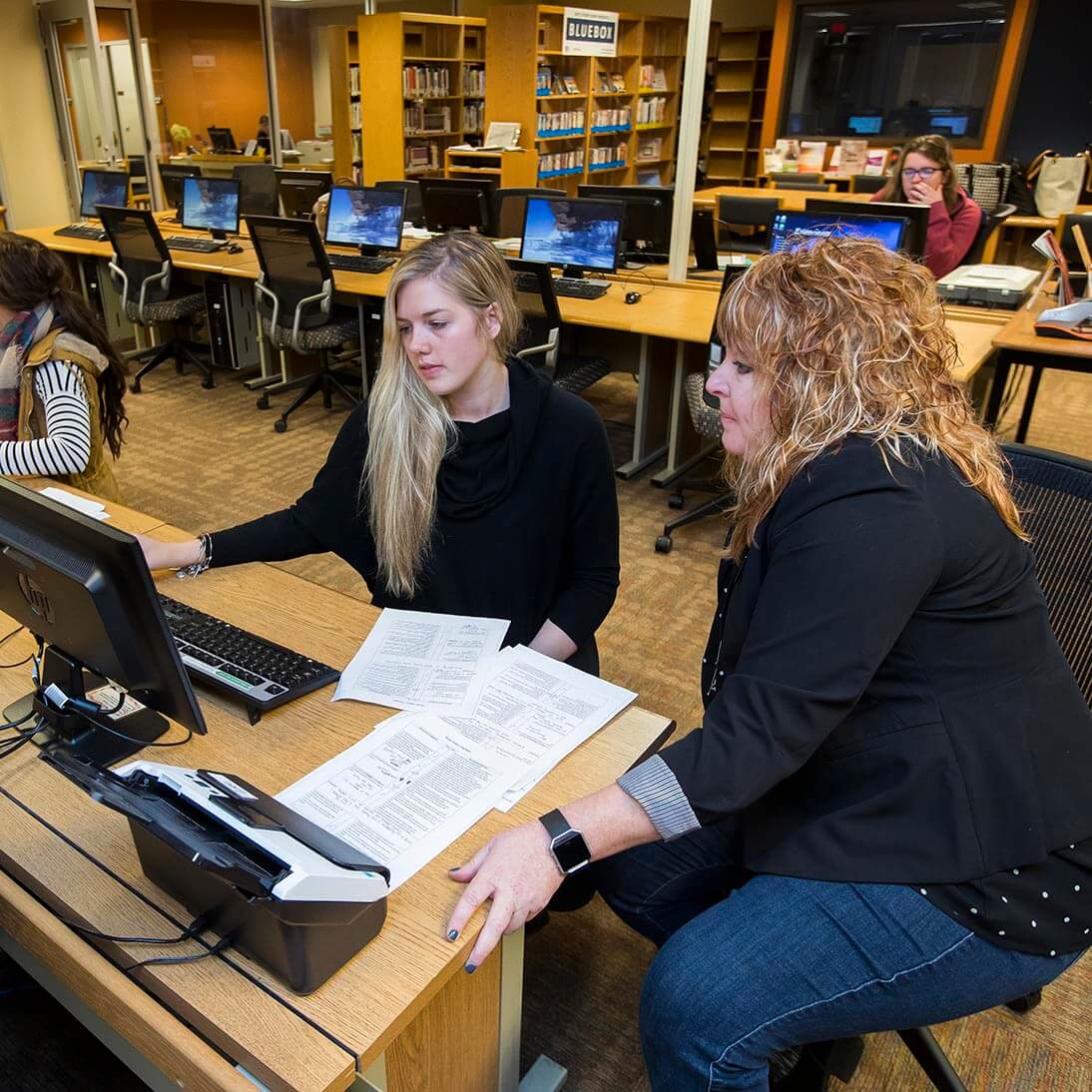 A student working on homework in the Learning Technology Center with support from staff
