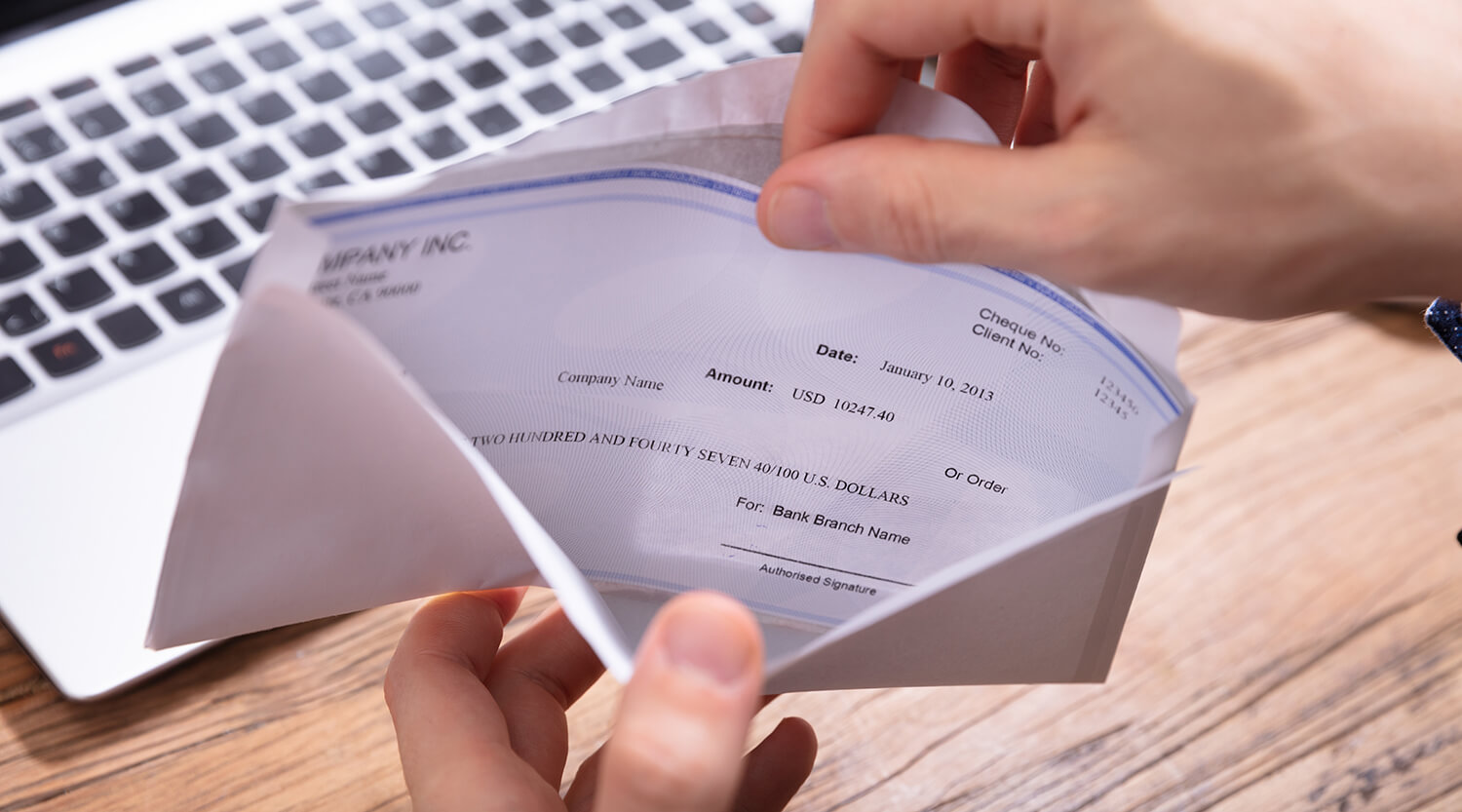 Close-up of someone opening an envelope with a pay stub in it