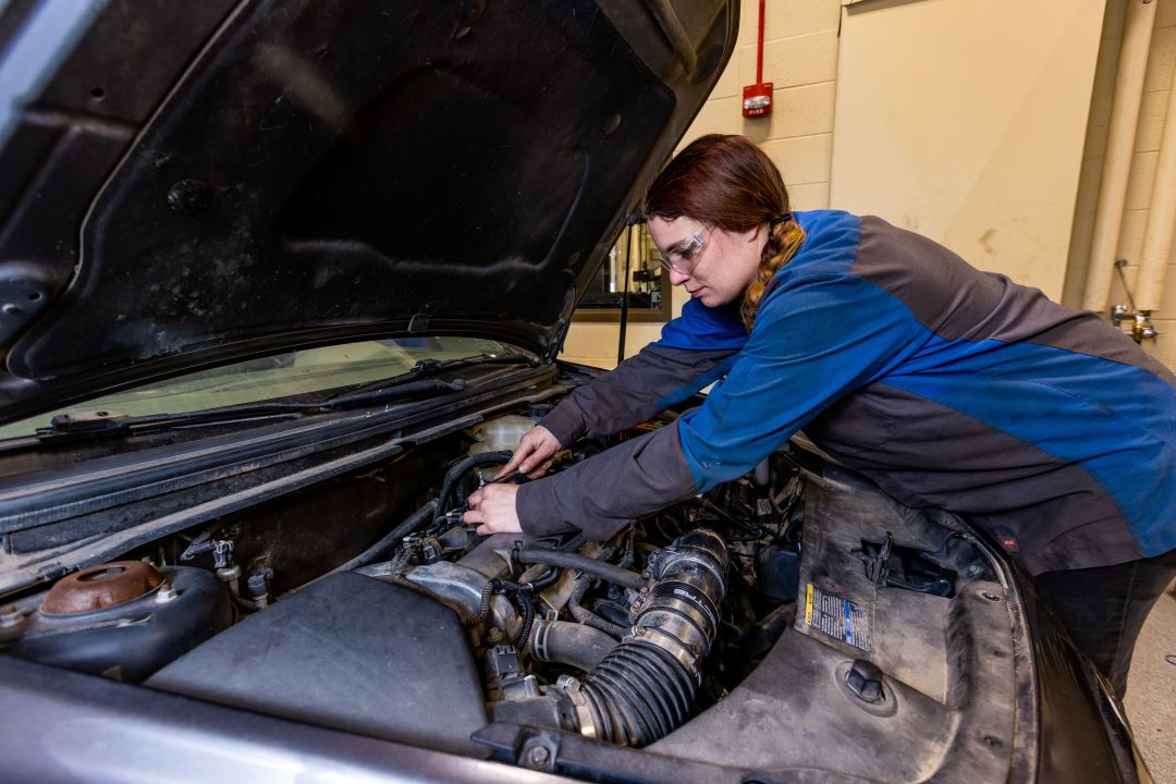 Automotive student working under the hood on car engine