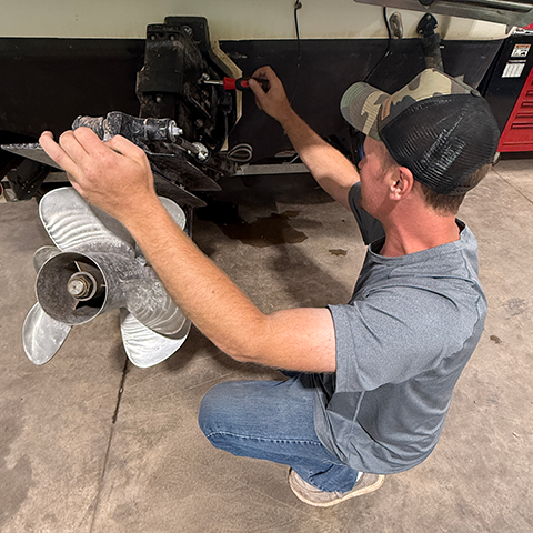 Technician at Lone Wolf Marine and Recreational in Mason, Wisconsin, repairing a boat motor in the service shop.