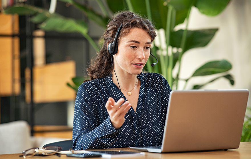 A business professional talking on a headset while looking at computer