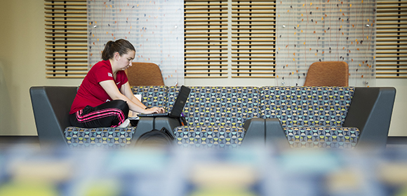 Woman sits at a booth working on her laptop