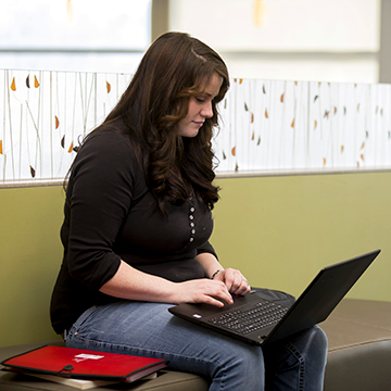 Student sitting on a bench and studying on a laptop