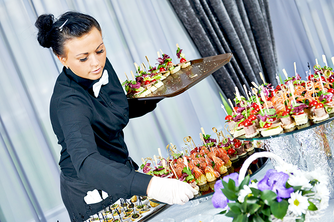 A caterer holding a tray of food 