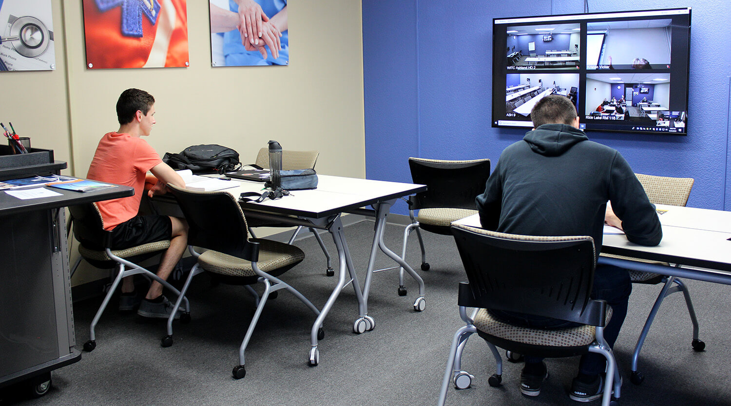 Students sitting in a classroom joining in with other students who are attending remotely