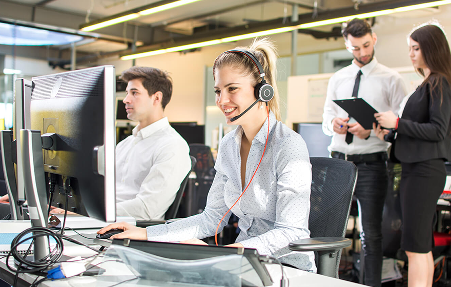 A customer service representative talking to a customer on a headset in a call center environment