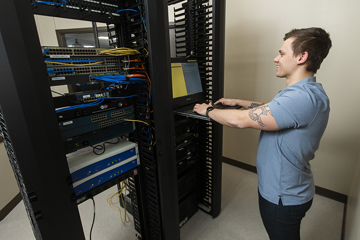 An IT - Cybersecurity Specialist student working hands-on with classroom technology