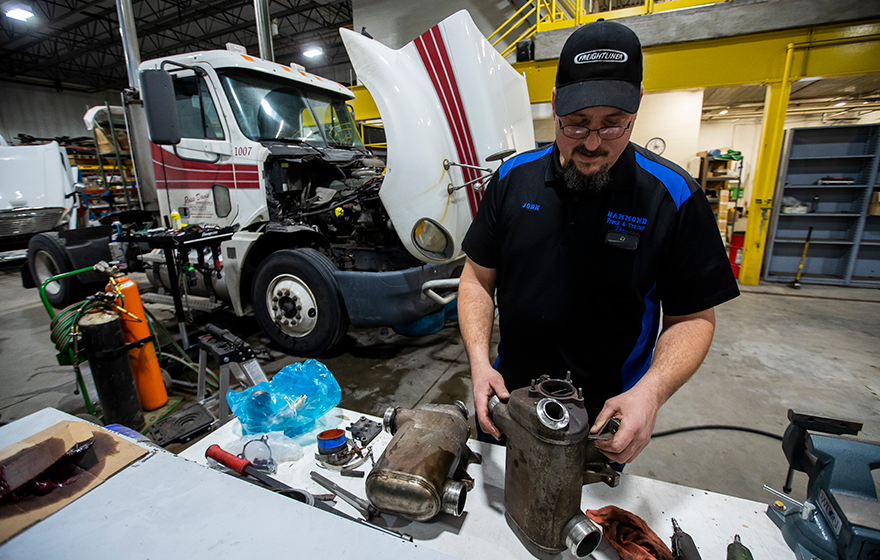 A diesel repair technician analyzing parts in a shop