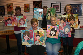 A group of students displays the pictures they painted during class.