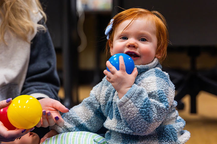 A toddler playing with pit balls in classroom