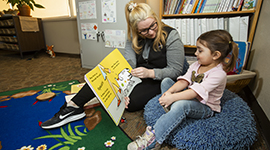 An Early Childhood Education student reading to a toddler-aged kid