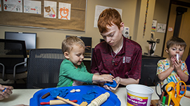 An Early Childhood Education student and a kid playing with Play-Doh