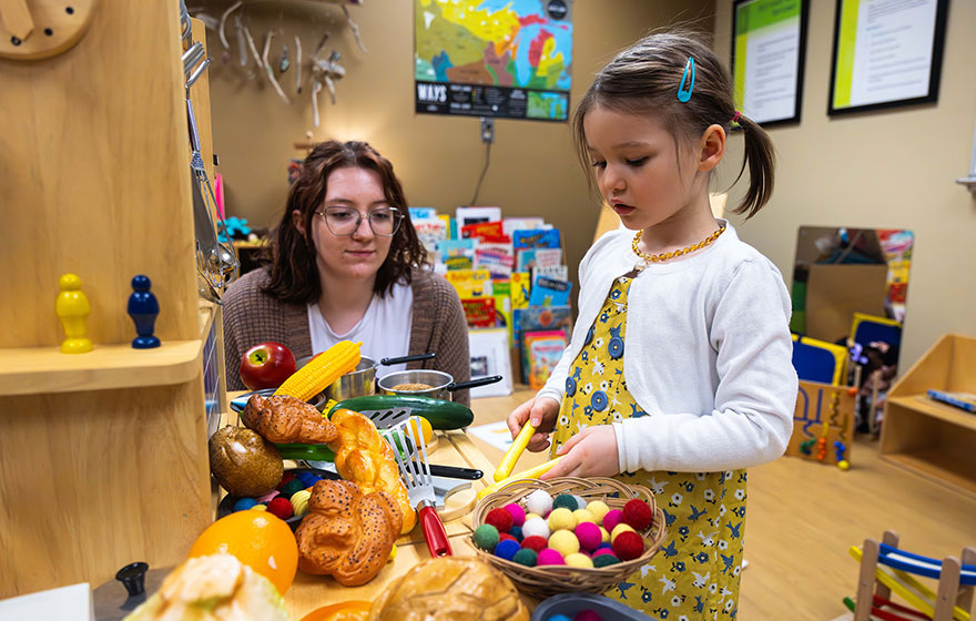 Early Childhood Education student and a child playing in a children kitchen set