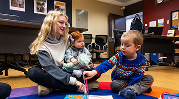 Student playing with two children in the classroom