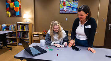 Early Childhood Education staff showing a student how to create kids arts and crafts