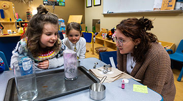 Student showing two children how to create bubbles