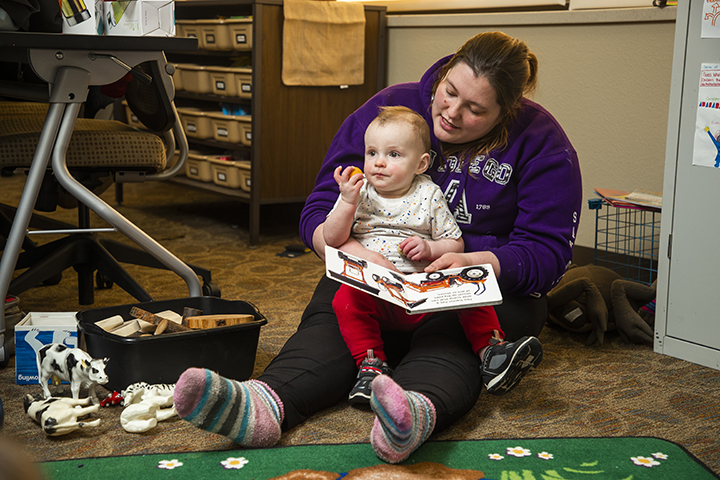 A student reading a book to a baby