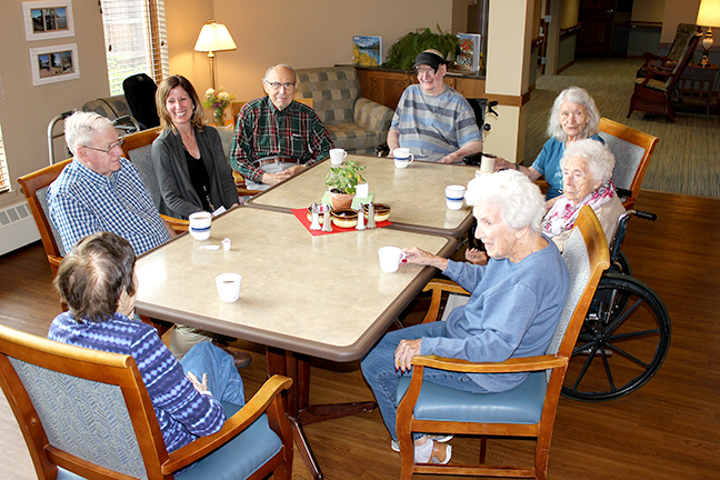 Group of residents in an assisted living facility sitting around a table and chatting over coffee
