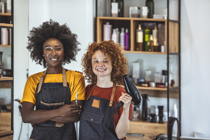 2 stylists pose in the front of their salon