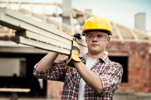 A construction worker carrying wood boards