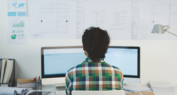 A web developer looking at three computer monitors