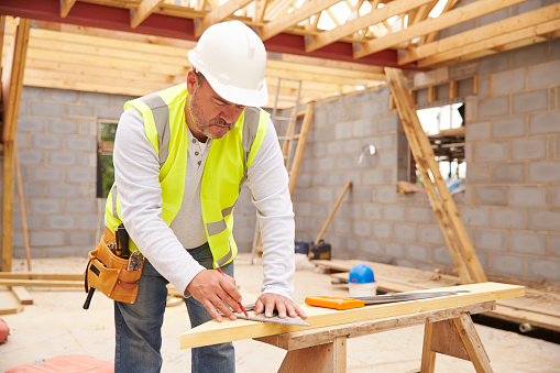 A carpenter cutting house roof supports on building