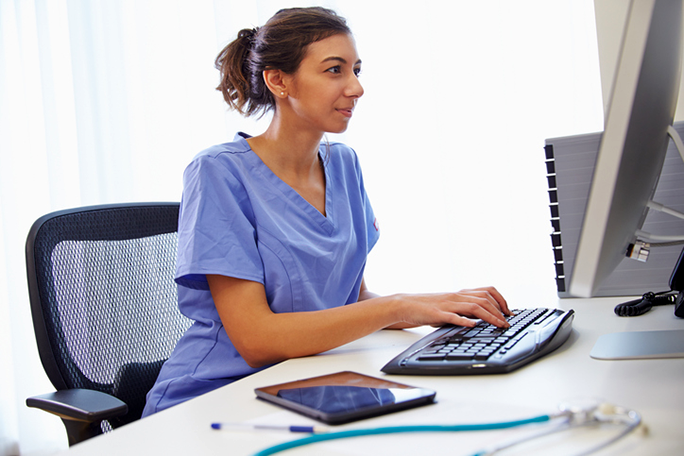 A medical office professional looking at a computer