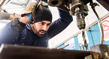 A worker at milling machine in workshop