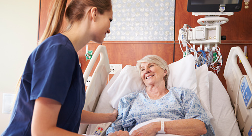 A nurse talking to a senior patient in a hospital bed