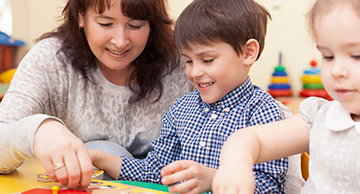 A teacher assistant helping kids put a puzzle together