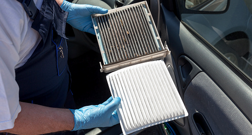 Worker comparing air conditioner filters from a vehicle