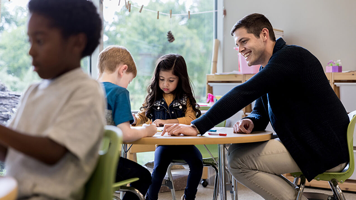 A child care worker helping preschool-aged kids