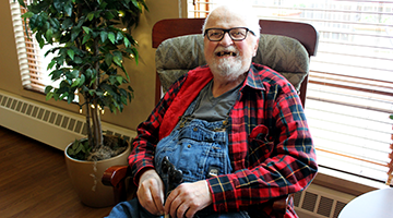 An aging adult sitting in a rocking chair and smiling