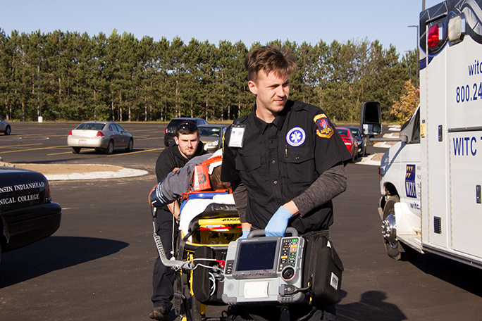An Emergency Medical Technician in training, carrying a stretcher