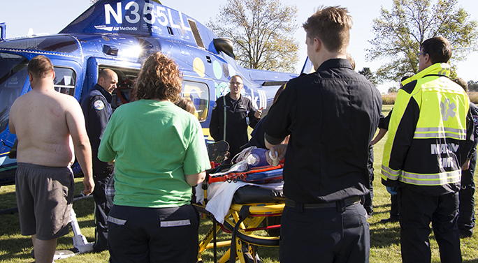 EMT students gathered around an instructor in front of a helicopter