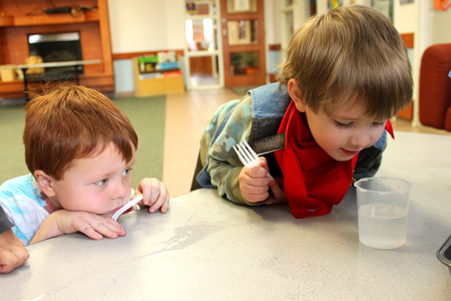 Two kids looking curiously at a science experiment