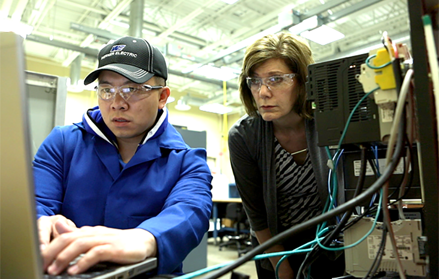 A student working on a computer and the instructor watching