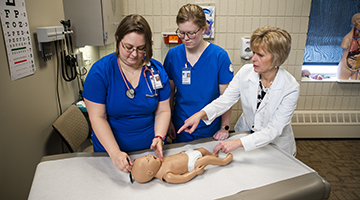Students learning how to measure a baby with help of instructor