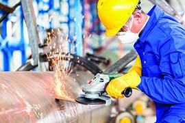 A work in full safety gear works with a grinder