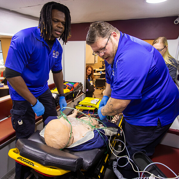 EMT students doing hands-on work with a simulated person