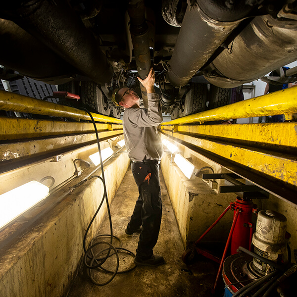 A diesel equipment technician student doing hands-on work underneath a truck