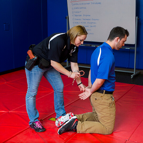 Academy students practicing putting handcuffs on a criminal