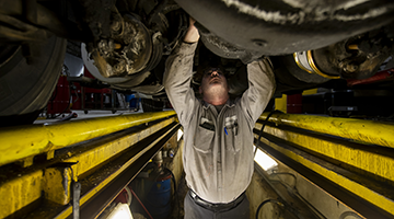 A diesel repair tech working underneath a truck